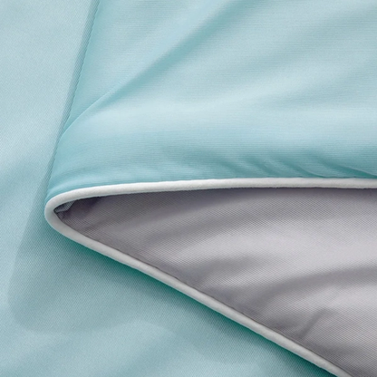 Närbild på dubbelvävd kant av isblått kyltäcke från NordicBlankets – visar kontrasten mellan sval utsida och grå insida i mjukt, andningsbart material